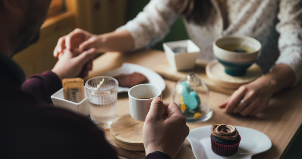 Two people holding hands having coffee